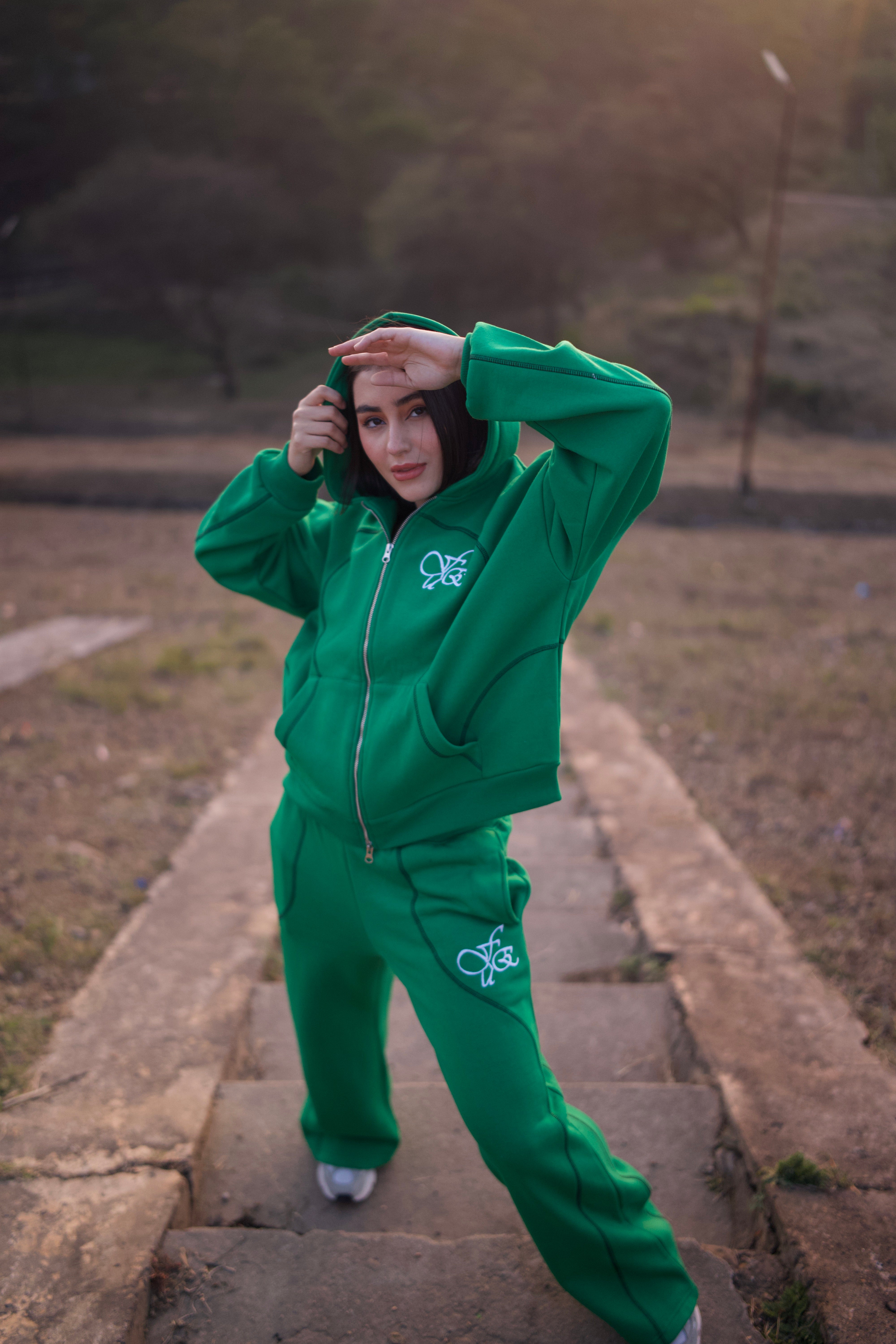 FUE Everyday Essential Sweatpants Green - model wearing green tracksuit on stone steps outdoors