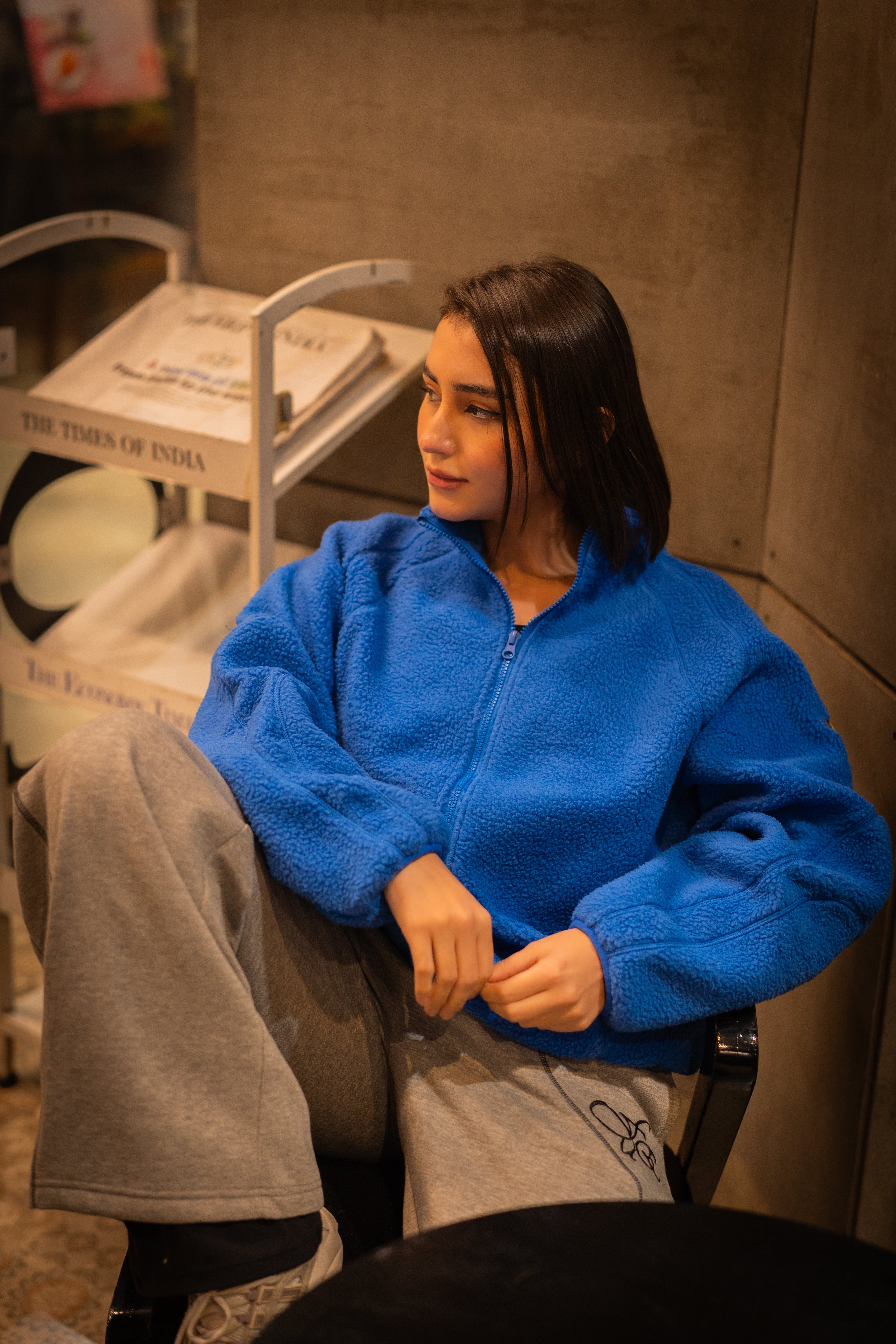 FUE Alpine Polar Fleece - female model wearing blue fleece jacket sitting indoors