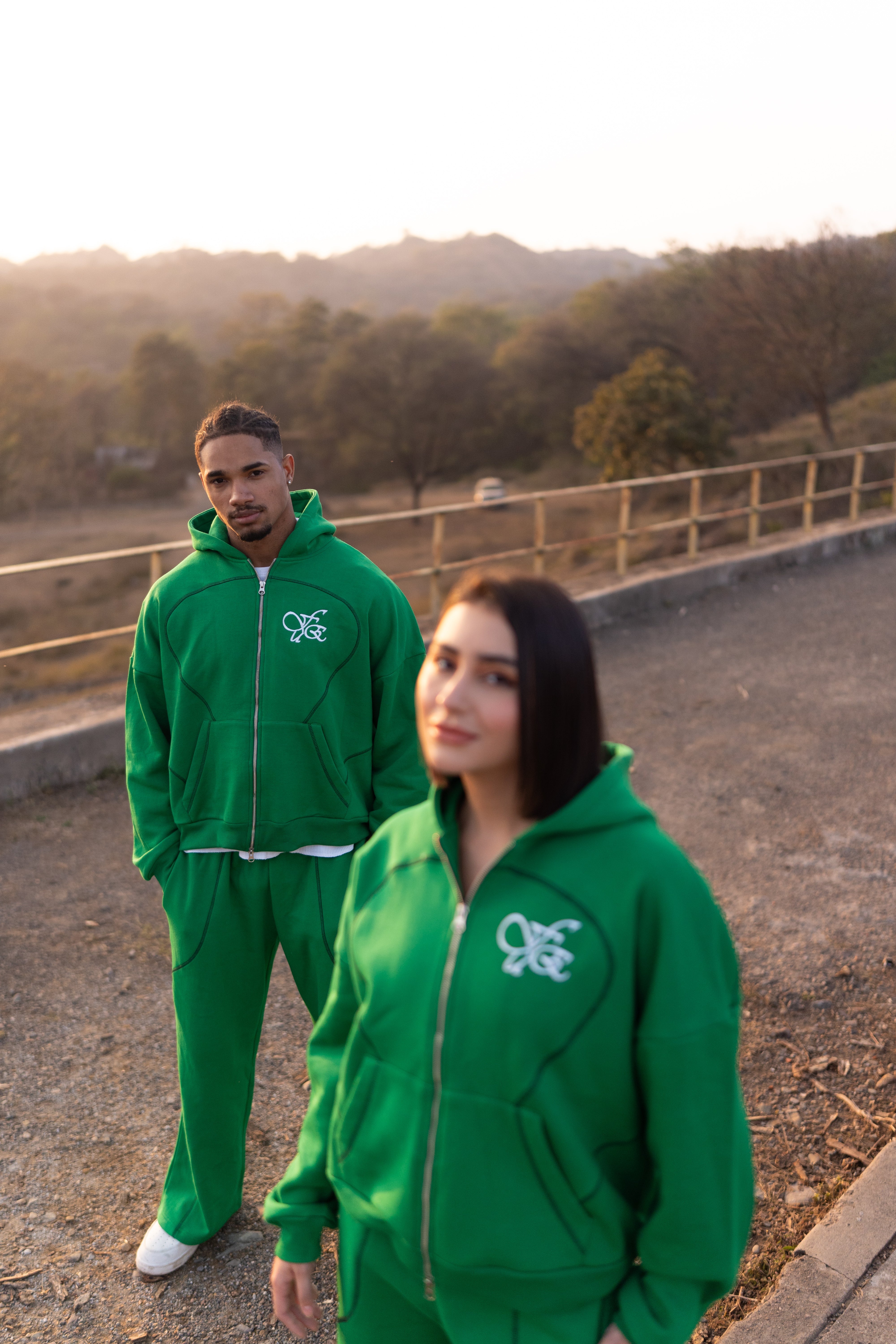 FUE Everyday Essential Sweatpants Green - two models in green tracksuits with FUE logo standing outdoors