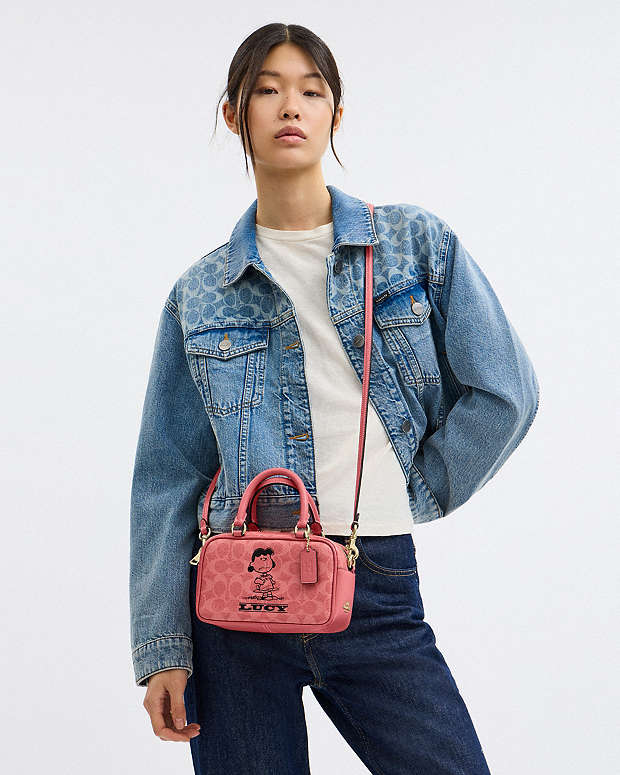 Coach X Peanuts Satchel Crossbody Bag In Signature Canvas With Lucy Signature Canvas-Im-Bright Coral Multi Signature Canvas-Im-Bright Coral Multi